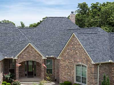 Front view of a higher-end, brick siding home with gray Malarkey asphalt shingles on its roof