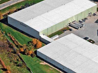 Two large warehouse buildings with a white, sloped roof with Mule-Hide products installed